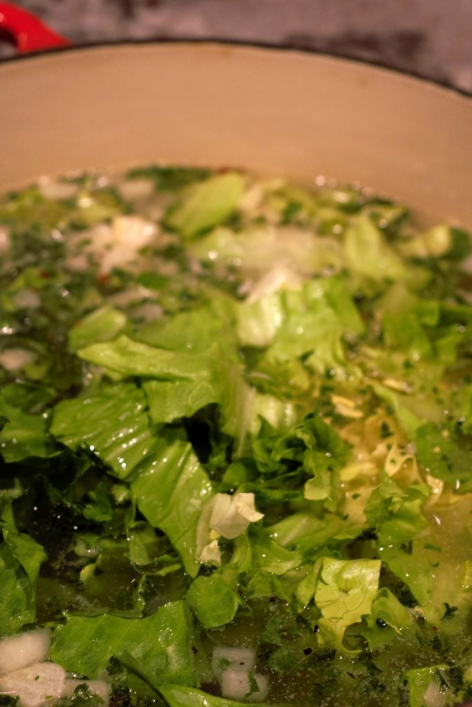 16 Cups of water are added and brought to a simmer. Cleaned and chopped escarole are added.