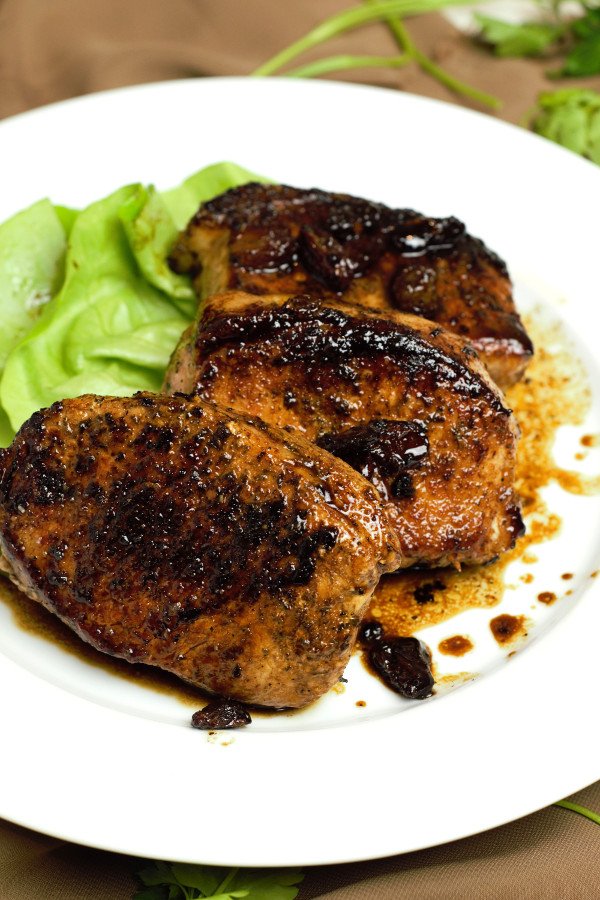 Perfectly Grilled Balsamic Glazed Boneless Pork Chops finished with a spoonful of glaze and dried cranberries.
