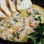 shrimp in butter sauce with bread and lemons