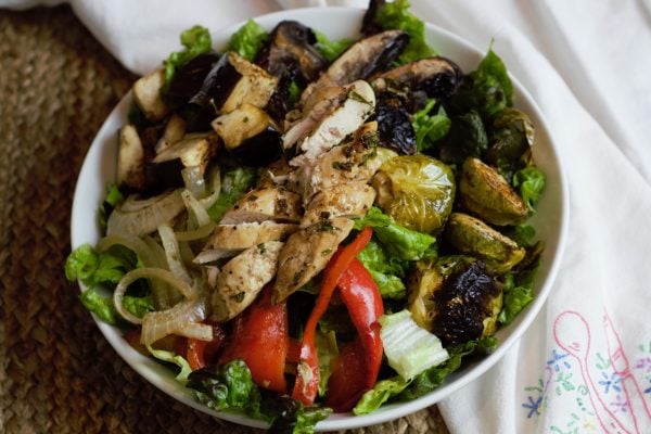 Balsamic Chicken 5 Bowl of bright and beautiful roasted vegetables with well browned chicken breast meat over red lettuce.
