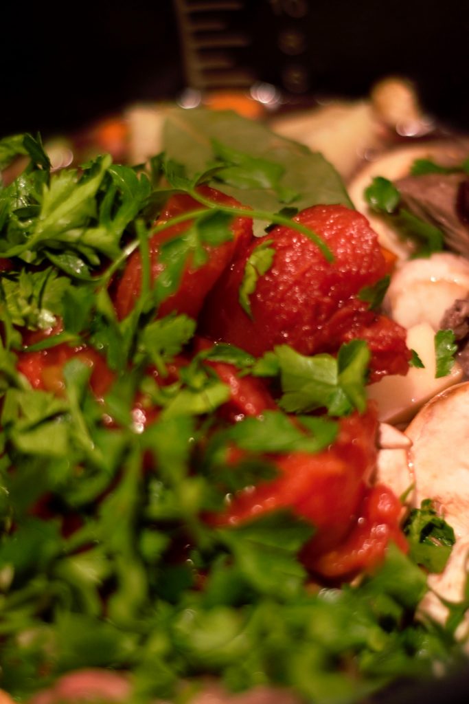 A can of stewed tomatoes, fresh parsley, bay leaves and red wine are added just before putting the lid on to cook.