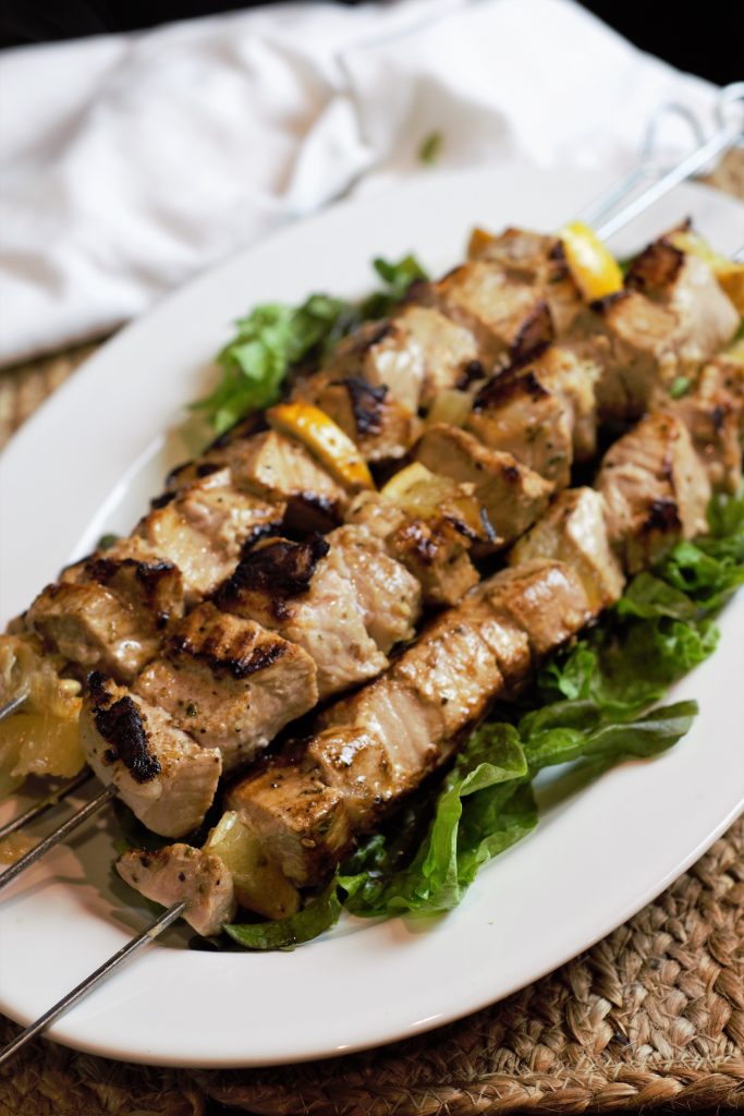 Pork Skewers on bed of greens on white plate