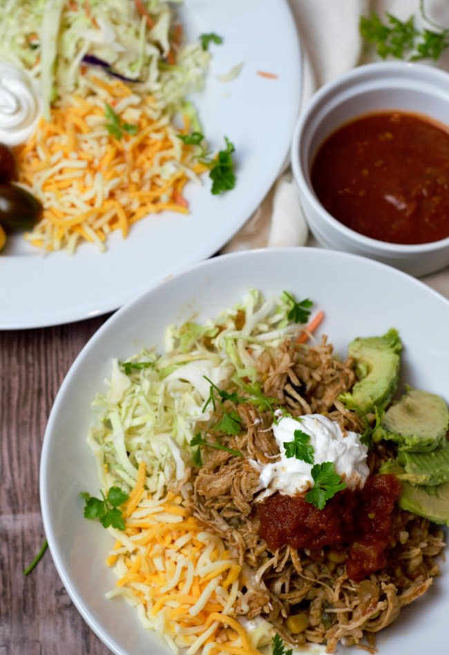 Chicken Taco bowl with a side of salsa and toppings.