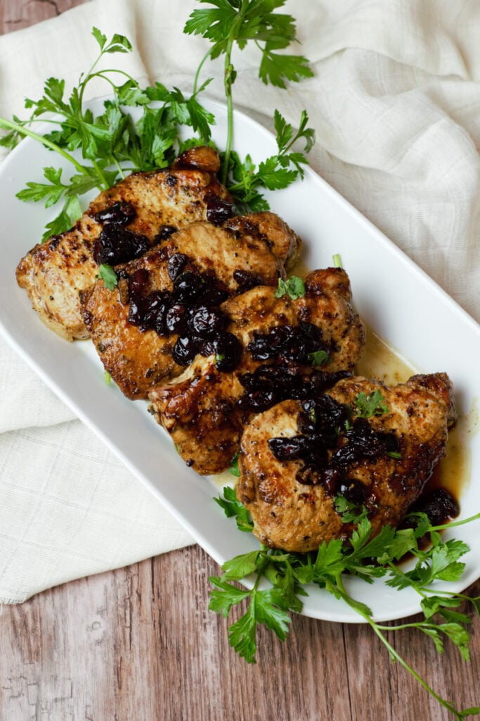 Four Pork Chops with cranberries on white plate