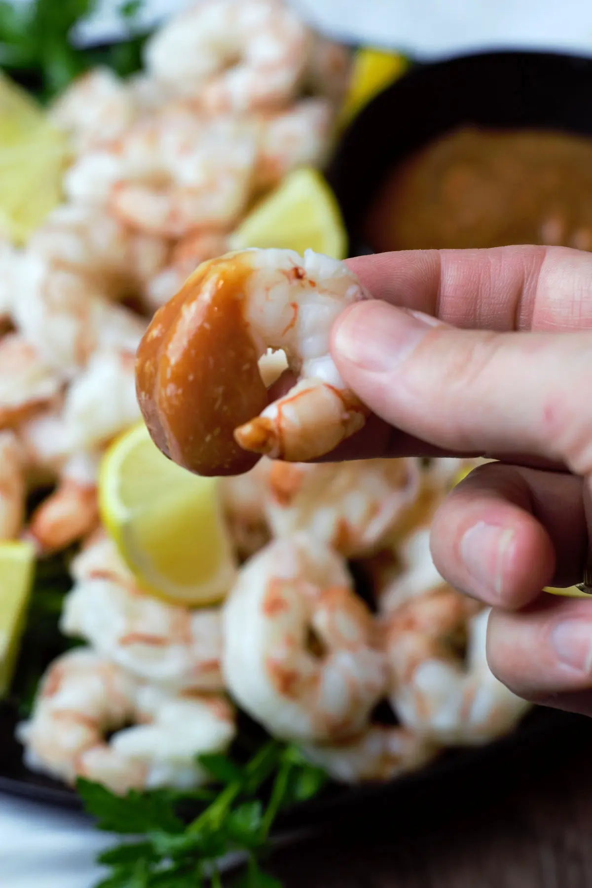 single shrimp with cocktail sauce in held in focus