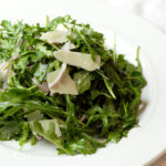 feature lemon arugula salad on white dish