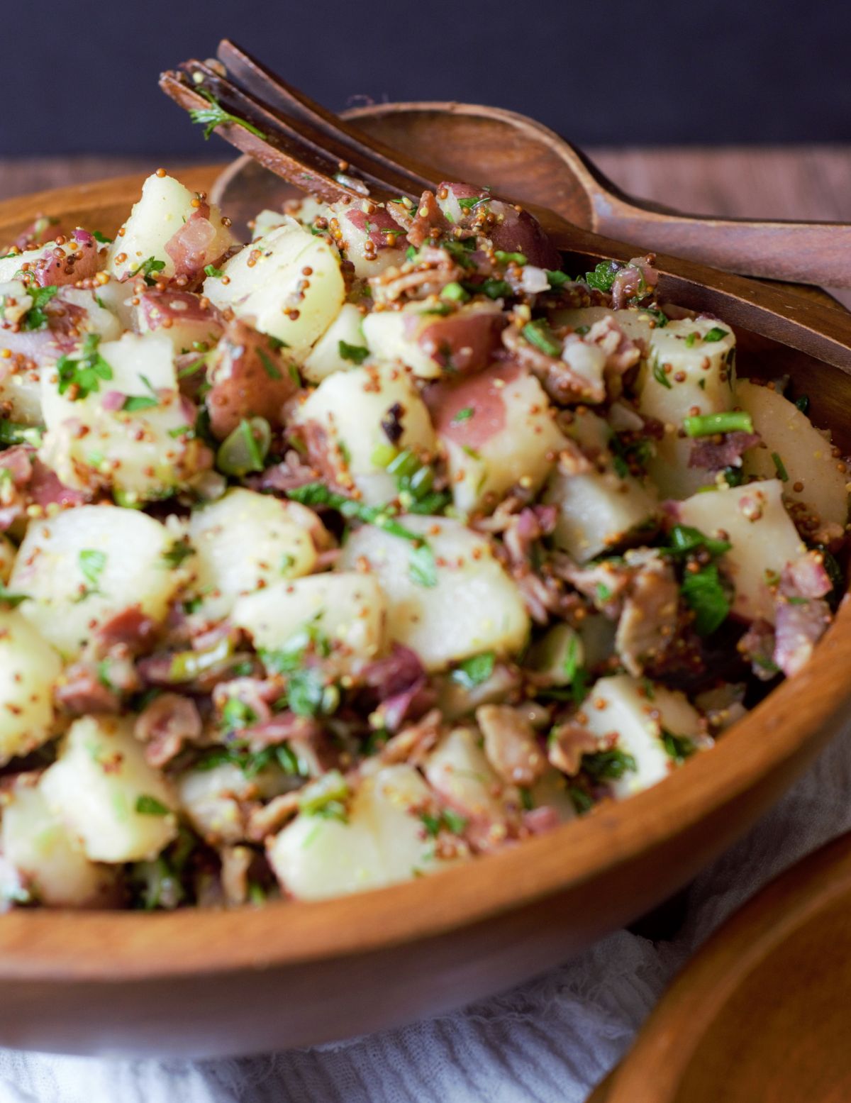 German Potato salad in a wooden bowl with serving spoons