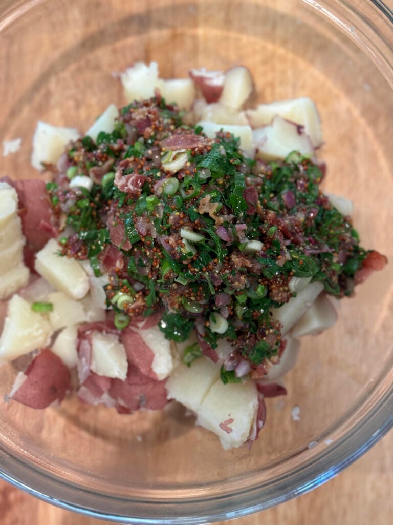 warm dressing on potatoes in a glass bowl