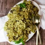 featured image pesto pasta salad with gold serving spoons on white plate