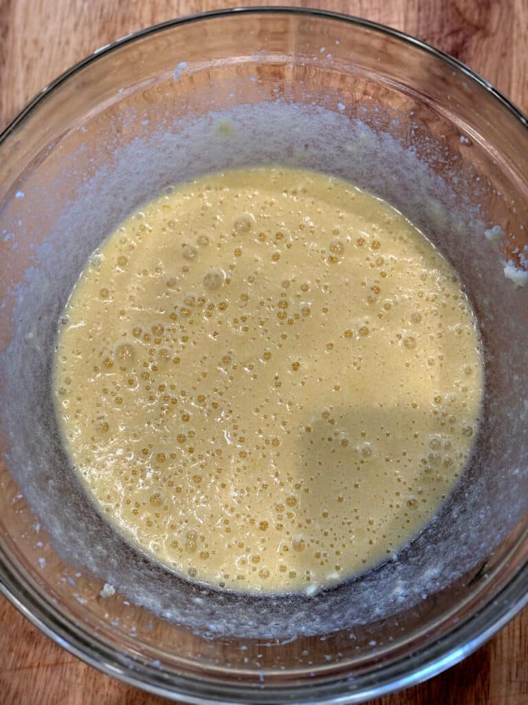 wet ingredients integrated into creamed butter in glass bowl