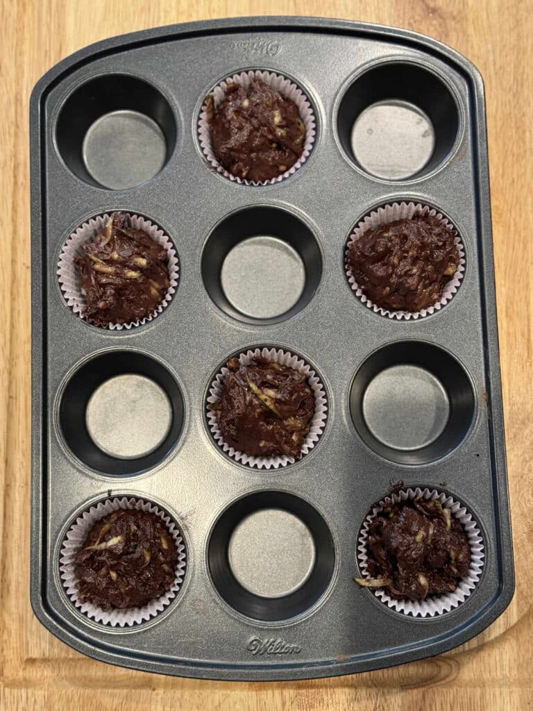 muffin tin half filled with muffin batter