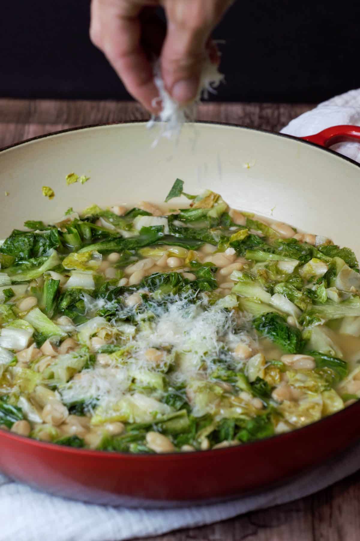 Parmesan cheese sprinkled over pot of greens and beans