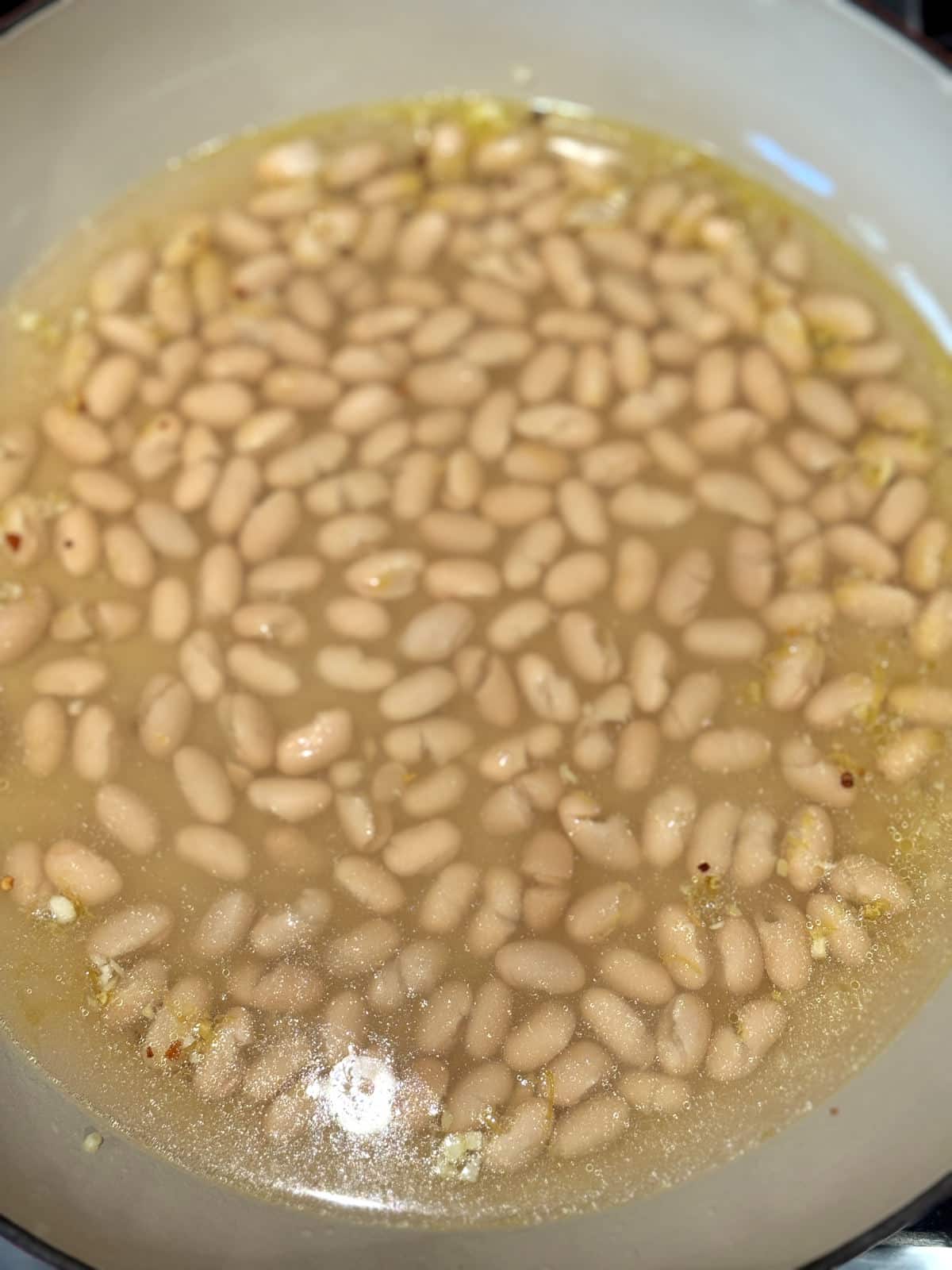 white beans simmering in seasoned broth