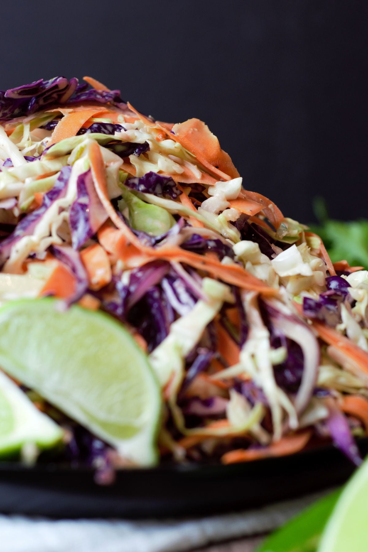 close up of dressed carrot and cabbage salad on black plate