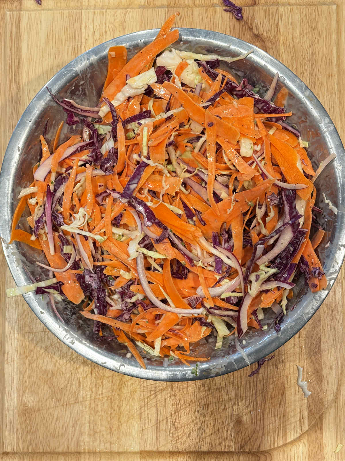 cabbage and carrot salad freshly mixed with dressing in large metal bowl