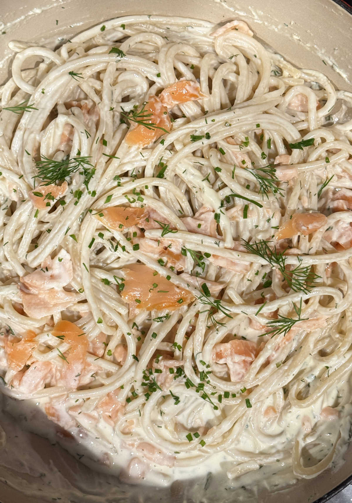 final step creamy smoked salmon pasta in Dutch oven with chive topping