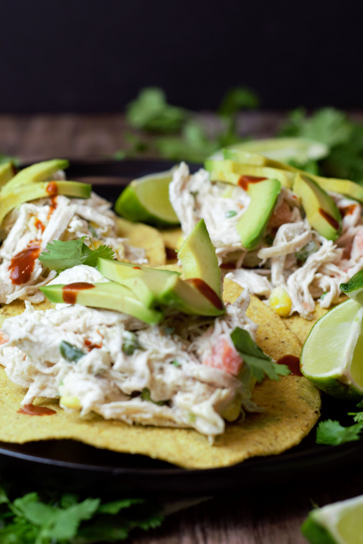 close up of three tostadas with chicken salad on black plate