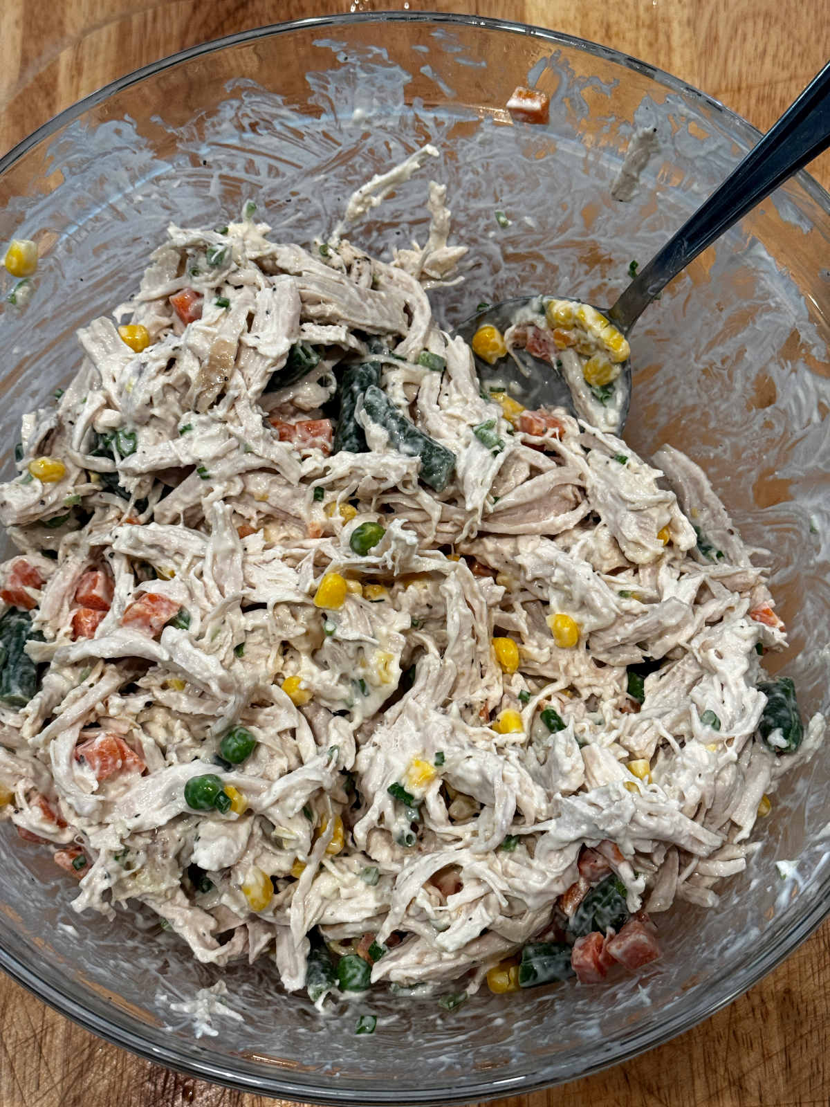 shredded chicken and vegetables mixed in a bowl with creamy dressing