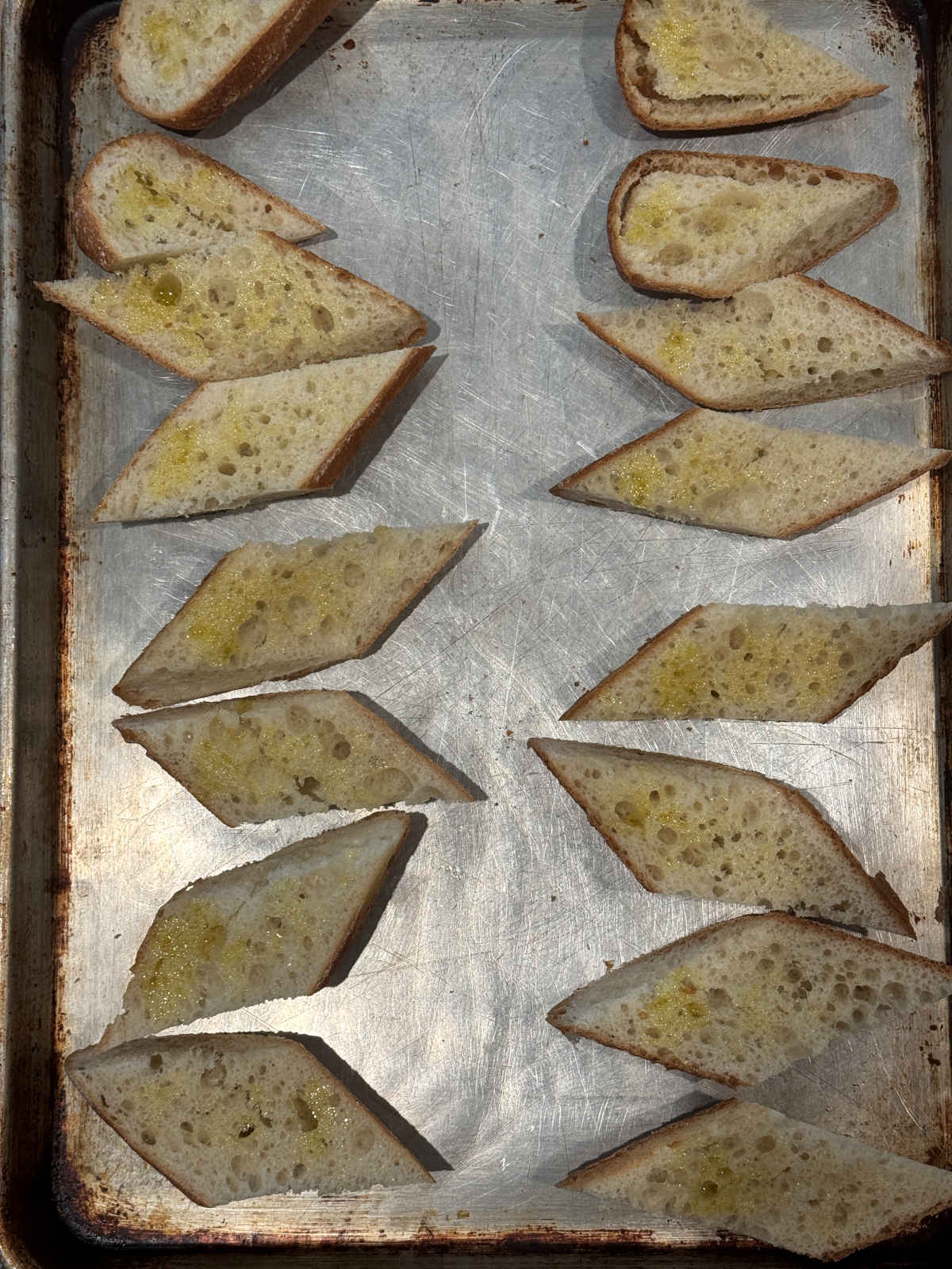 French bread slices with olive oil on sheet pan