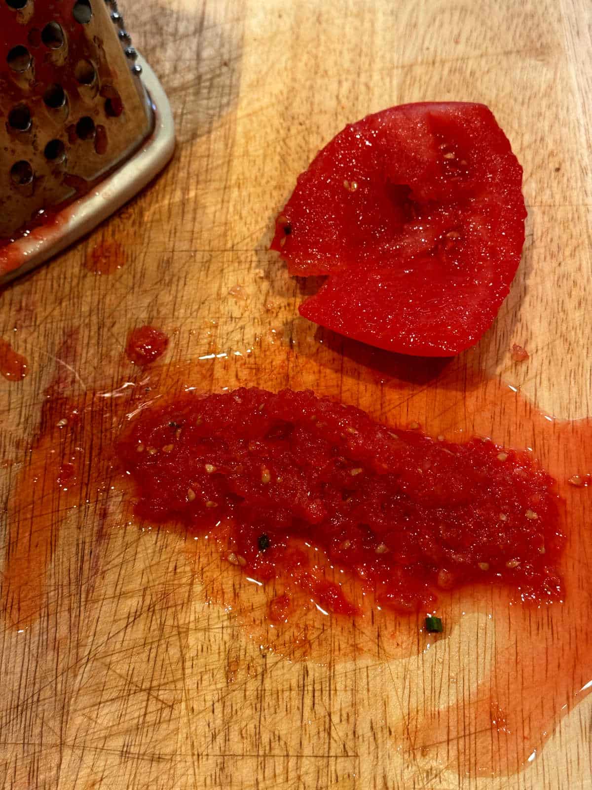half a tomato grated onto a wood cutting board