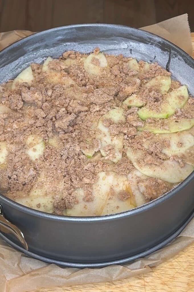 all of the layers of cake, apples, and streusel in cake pan