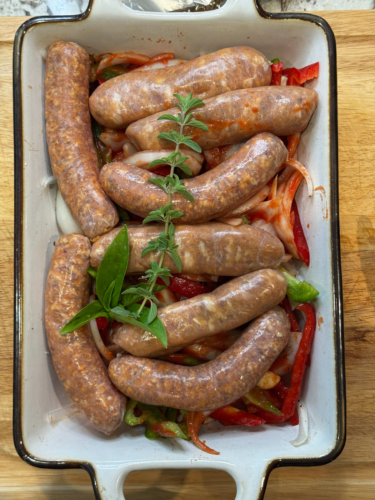 Raw sausage and peppers in a baking dish